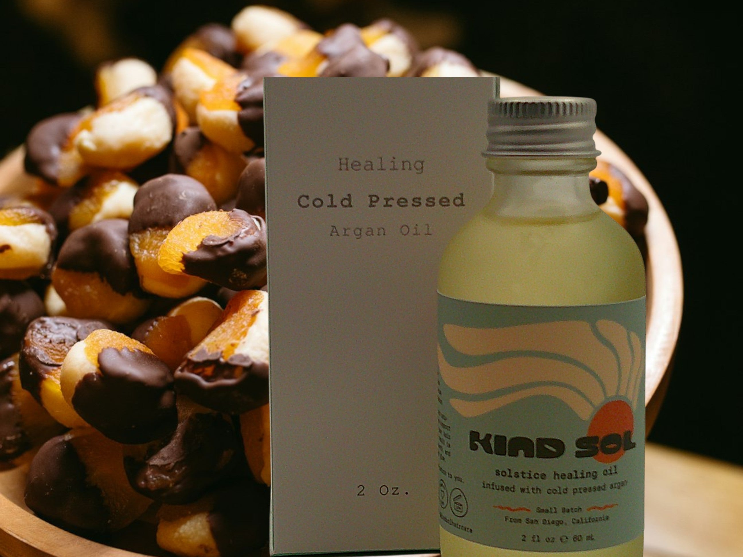 Bottle of Kiad Sol healing cold pressed argan oil with packaging and argan nuts in the background.