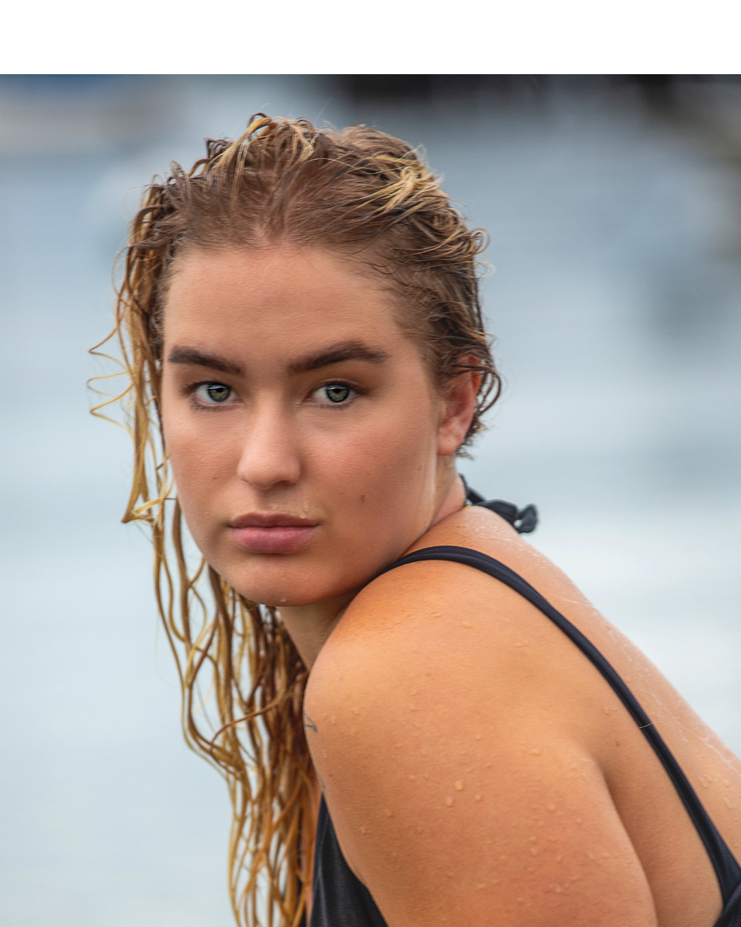girl holding a surfboard enjoying the ocean knowing her hair is protected